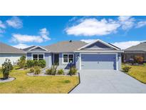 Charming single-story home features a two-car garage, manicured lawn, and beautiful landscaping under a bright sky at 1959 Keel Ct, The Villages, FL 34762