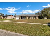 Charming single-story home with well-maintained lawn and attached one car garage, under a bright blue sky at 4207 Chateau Rd, Orlando, FL 32808