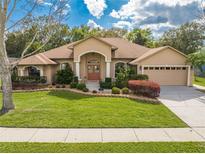 Charming single-story home featuring a manicured lawn, mature landscaping, and an attached two-car garage at 4933 Raylene Way, St Cloud, FL 34771