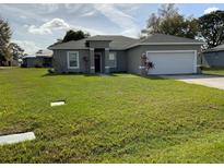 Well-maintained home with a lush green lawn and a two-car garage at 1958 Sawfish Dr, Kissimmee, FL 34759