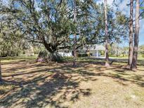 Quaint single story home with covered parking surrounded by mature trees and flowering bushes at 11207 Roberson Rd, Winter Garden, FL 34787