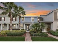 Charming townhome with lush landscaping, brick pathway, and palm trees at sunset at 12024 Sonnet Ave, Orlando, FL 32832