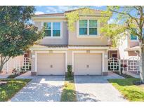 Charming two-story townhome with tan stucco, matching garage doors, and tile roof at 1244 Romani Ave # 1244, Davenport, FL 33896