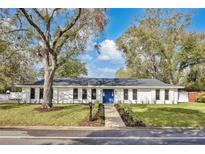 Charming one story home with a blue door, landscaped yard, and mature trees at 1536 Errol Pkwy, Apopka, FL 32712