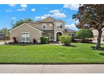 Charming two-story home boasting a well-manicured lawn and mature landscaping on a sunny day at 558 Osprey Lakes Cir, Chuluota, FL 32766