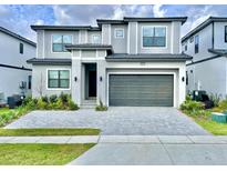 Modern two-story home featuring a gray brick driveway, lush landscaping, and an attached two-car garage at 10012 Voyager Way, Orlando, FL 32821