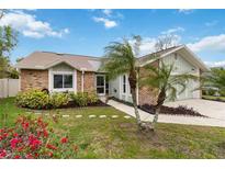 Charming brick home with a well-manicured lawn, landscape and mature palm trees at 1071 Sweet Tree Ct, Apopka, FL 32712