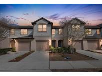 Beautiful townhome exterior with neutral paint, garage, and manicured landscaping at dusk at 1117 Pavia Dr, Apopka, FL 32703