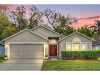 Charming single-story home featuring a well-maintained lawn, two car garage, and inviting front entrance with a red door at 137 Golfside Cir, Sanford, FL 32773