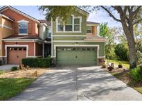 Two-story townhouse with a two-car garage, stone accents, and a long driveway and manicured lawn at 2015 Shalimar Loop, Sanford, FL 32773