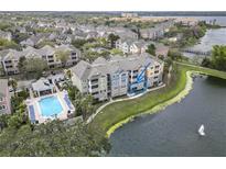 Aerial view of condo building next to lake and pool, featuring outdoor patio with blue accents at 3344 Corona Village Way # B4, Orlando, FL 32835