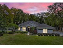 Charming single-story home with manicured lawn, mature trees, and inviting curb appeal at dusk at 8176 Emerald Forest Ct, Sanford, FL 32771