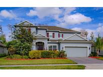 Charming two-story home featuring a well-manicured lawn, mature landscaping, and a two-car garage at 14031 Jomatt Loop, Winter Garden, FL 34787