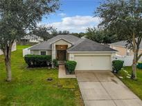 Charming single-story home featuring a well-manicured lawn and an attached two-car garage at 2413 Sandridge Cir, Eustis, FL 32726