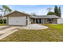 Charming single-story home featuring a two-car garage and quaint front yard with decorative rock and blue shutters at 409 Surrey Run, Casselberry, FL 32707