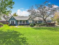 Charming single story home featuring well-manicured lawn, beautiful landscaping, and a lovely, traditional-style porch at 418 Norwood Ct, Oviedo, FL 32765