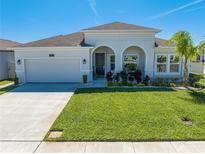 Charming one-story home featuring arched entryway, lush lawn, and attached two-car garage at 5301 Amersham Ln, St Cloud, FL 34771