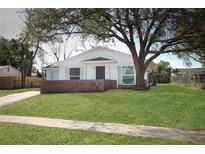 Charming single-story home featuring a well-manicured lawn, a brick accent wall and a large shade tree at 6222 Fox Hunt Trl, Orlando, FL 32808