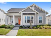 Charming single-Gathering home featuring a well-manicured lawn and an inviting orange front door at 936 Allendale Ln, Winter Garden, FL 34787