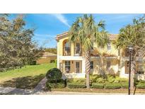 Charming two-story home with a yellow exterior, red tile roof, balcony, and lush landscaping at 12016 Lorenza Ln, Orlando, FL 32827