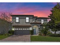 Charming two-story home featuring a brick driveway, gray stucco, and a tile roof at 1412 Moon Valley Dr, Davenport, FL 33896