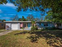 Charming single-story home featuring a quaint stone porch, light blue door, white garage door, and manicured front lawn at 1700 Edmundshire Rd, Orlando, FL 32812