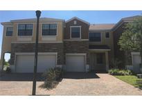 Two-story townhome showcasing a brick driveway, two-car garage, and well-maintained front yard at 1973 Portofino Meadows Blvd, Orlando, FL 32824