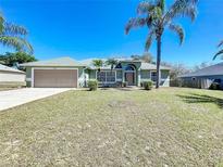 Charming single-story home with a two-car garage, arched entry, and tropical landscaping at 2253 Lake Pointe Cir, Leesburg, FL 34748