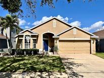 Charming one-story home with a well-manicured lawn, lush landscaping, and a striking blue front door at 2707 Barnsley Ln, Kissimmee, FL 34744