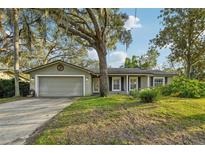 Charming single-story home with mature trees, well-kept lawn, and a two-car garage on a sunny day at 101 Ludlow Dr, Longwood, FL 32779