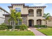 Charming two-story home features a stone facade, stucco accents, and a manicured lawn with tropical landscaping at 10236 Beechwood Ln, Orlando, FL 32832