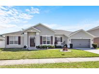 Charming single-story home features a manicured lawn, two-car garage, and welcoming front entrance with decorative accents at 2168 Continental St, St Cloud, FL 34769