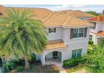 Charming two-story townhome featuring a tile roof, arched entry, and tropical landscaping at 4865 Clock Tower Dr, Kissimmee, FL 34746