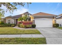 Charming one-story home featuring a lush lawn, mature landscaping, and a two-car garage at 13711 Dornoch Dr, Orlando, FL 32828