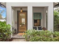 Inviting front porch with a wood door, lantern lighting, bench seating, and lush landscaping at 1429 Indiana Ave, Winter Park, FL 32789