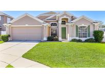 Charming single-Gathering home boasts lush lawn, verdant green door and a two-car garage at 2534 Wekiva Walk Way, Apopka, FL 32703