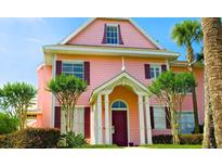 Eye-catching two-story pink house with inviting front door and charming, manicured landscaping at 3000 Limbo Ln # 102, Kissimmee, FL 34746