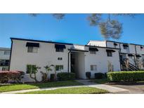 Two-story condo features classic black awnings, clean white paint, and lush landscaping at 4205 S Semoran Blvd # 3, Orlando, FL 32822