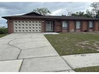 Charming single-story home with a two car garage and well-maintained landscaping and a cracked driveway at 6567 Magee Ct, Orlando, FL 32818