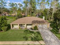 Charming single-story home with a well-manicured lawn, mature trees, and a long driveway at 109 Sweetwater Oaks Ln, Daytona Beach, FL 32114