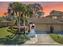 Inviting exterior view of townhome with mature palm trees and colorful landscaping against an orange tinted sky at 133 Heron Bay Cir, Lake Mary, FL 32746