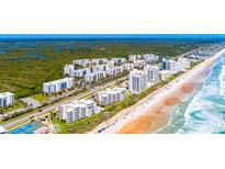 An elevated view of beachfront condos, and pristine shoreline along the ocean with lush greenery nearby at 5300 S Atlantic Ave # 7-301, New Smyrna Beach, FL 32169
