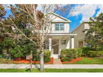 Charming two-story home with a manicured lawn and cozy front porch, complemented by lush landscaping at 8321 Bryce Canyon Ave, Windermere, FL 34786