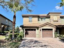 Two-story home featuring a two-car garage, nicely landscaped yard and a brick driveway at 8923 Azalea Sands Ln, Davenport, FL 33896