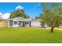 Charming single-story home featuring a lush green lawn, gray brick accents, and a well-maintained gray roof at 150 Chicago Woods Cir, Orlando, FL 32824