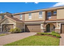 Townhouse exterior with brown garage doors, stone accents, and a well-maintained lawn at 2165 Leather Fern Dr, Ocoee, FL 34761