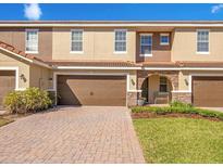 Charming townhome with a two-car garage, stone accents, and well-maintained landscaping at 2165 Leather Fern Dr, Ocoee, FL 34761