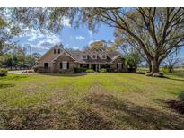 Sprawling ranch home with stone and siding exterior, dormer windows, mature trees, and a well manicured lawn at 31707 Orange St, Sorrento, FL 32776