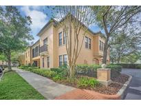 Stucco townhome with neat landscaping, side walk, and mature shade trees at 506 Mirasol Cir # 202, Celebration, FL 34747