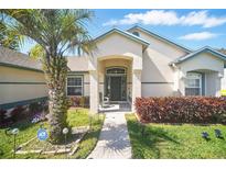 Charming home featuring a covered front entrance, lush landscaping, and a well-manicured lawn at 872 High Pointe Cir, Minneola, FL 34715